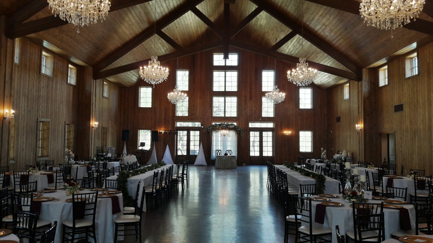 Elegancka sala weselna z udekorowanymi stołami i żyrandolami.